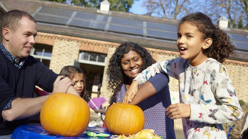 Close up of a family carving pumpkins at a table outside